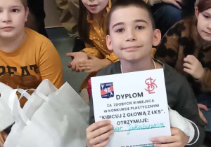 Uczeń klasy 3b z dyplomem i nagrodami za zajęcie III miejsca w konkursie plastycznym.