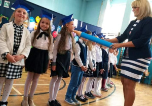 Pani dyrektor Monika Siedmiogrodzka pasuje uczniów.