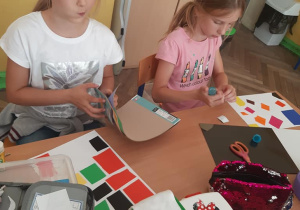 Uczennice wycinają i naklejają elementy z papieru kolorowego
