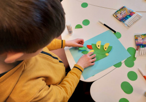 Uczeń klasy 1a podczas twórczej pracy_wykonanie smoka z kolorowych kółek.