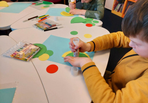 Uczniowie klasy 1a podczas twórczej pracy_wykonanie smoka z kolorowych kółek.