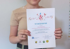 Uczennica klasy Va, Julia Klukiewicz z dyplomem i nagrodami za zdobycie wyróżnienia.