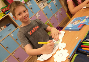 Uczeń klasy 1a podczas twórczej pracy z kartoniakami.