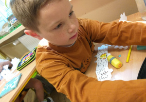 Uczeń klasy 1a podczas twórczej pracy z kartoniakami.