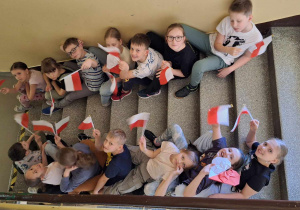 Uczniowie klasy 3a podczas klasowych obchodów świąt majowych_pamiatkowe zdjęcia z flagami Polski.