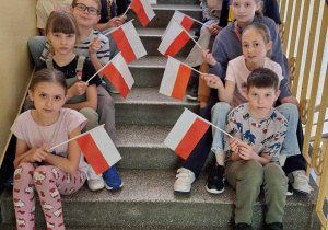 Uczniowie klasy 3a podczas klasowych obchodów świąt majowych_pamiatkowe zdjęcia z flagami Polski.