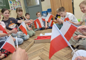 Uczniowie klasy 3a podczas klasowych obchodów świąt majowych_pamiątkowe zdjęcie z flagami Polski.