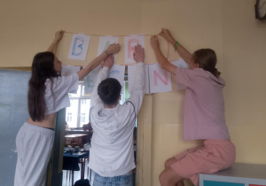Uczniowie klasy 8a zawieszający transparent reklamowy_Bar Mleczny.