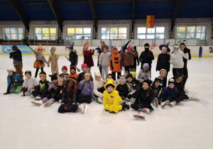 Zabawa halloweenowa klas łyżwiarskich na lodowisku w Hali Bombonierka_klasa 1a i 2a_pamiątkowe zdjęcie grupowe.