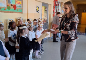 Uroczyste pasowanie pierwszoklasistów na Czytelnika_moment wręczenia pamiątkowych dyplomów i zakładek.