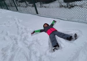 Zimowe szaleństwa na śniegu w klasie 1a_uczennica wykonuje orzełka na śniegu.