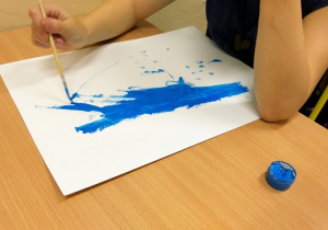 Uczeń maluje farbami.