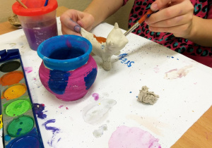 Uczeń maluje wykonanego z gliny kota