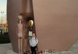 Uczeń stoi przed pomnikiem Martyrologii Dzieci w Parku Promienistych