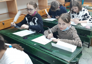 Dzieci w trakcie kaligrafii gęsim piórem