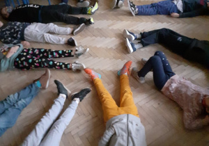 Uczniowie leżą na podłodze