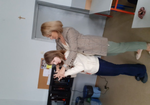 Uczennica trzyma aparat fotograficzny. Nauczycielka pomaga jej.