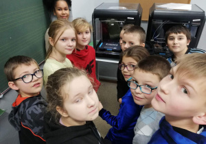 Uczniowie klasy 4b na tle drukarek 3D.