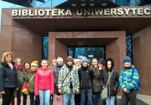 Uczniowie stoją przed budynkiem Biblioteki Uniwersyteckiej.